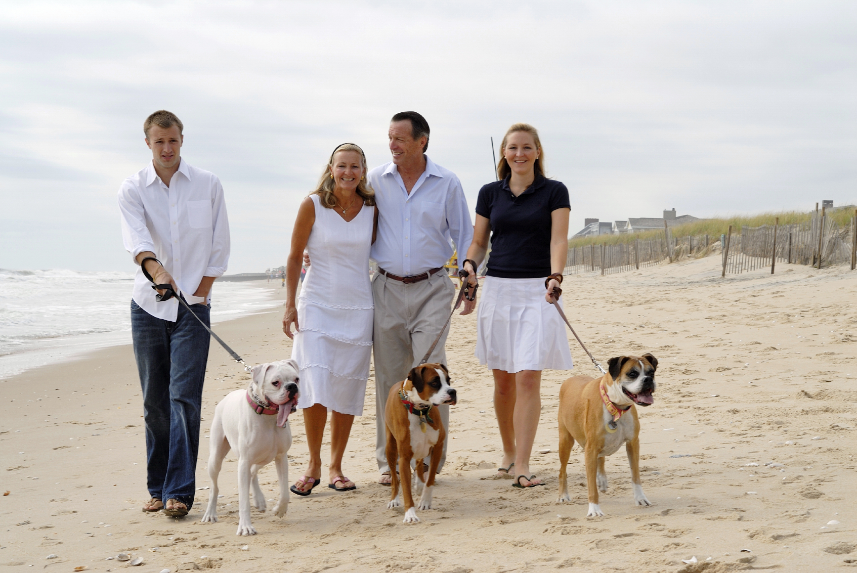 two couples walking their dogs on the beach